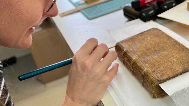 close up of woman's profile with tool working on spine of book