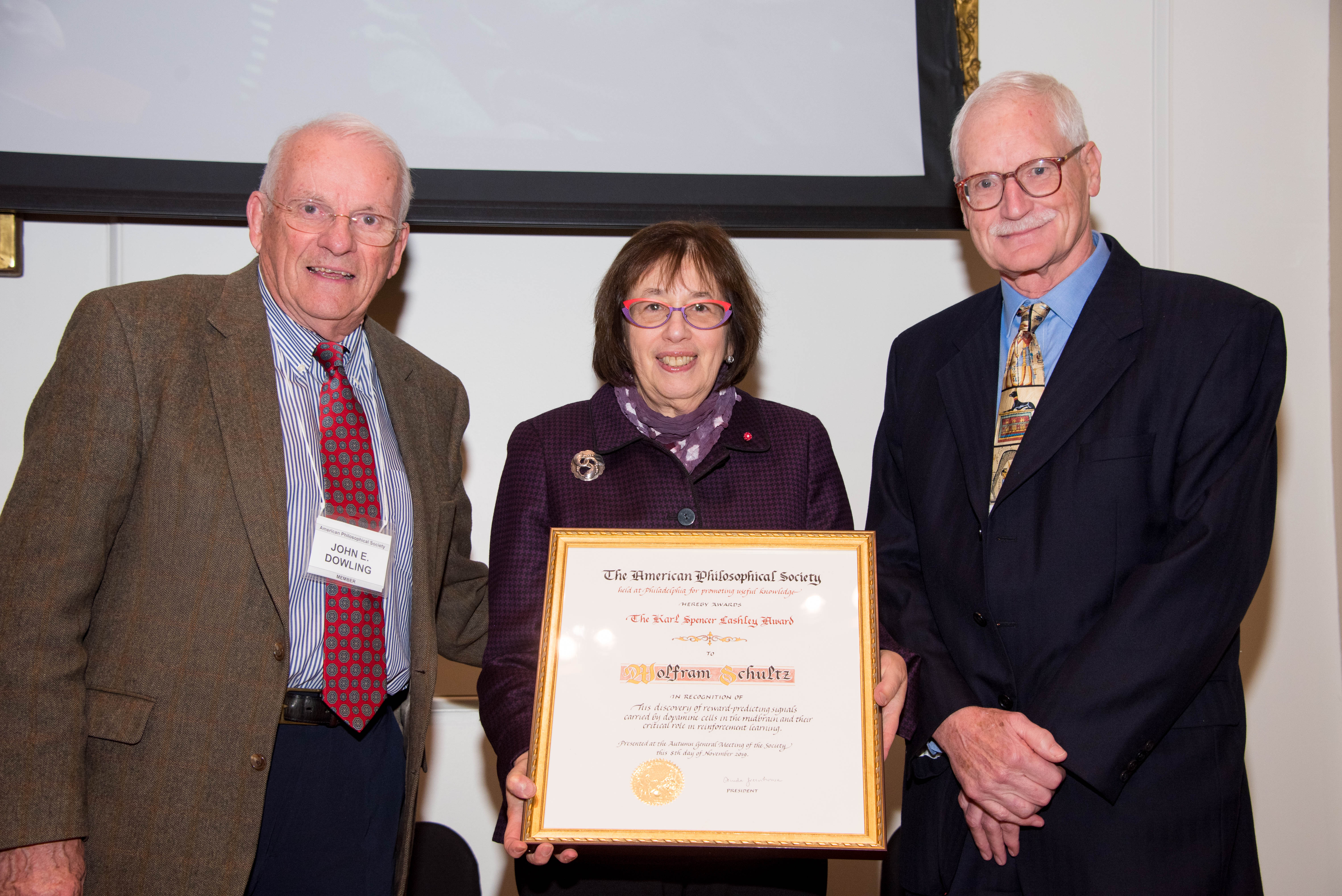 Linda Greenhouse Holds the Lashley Award certificate, standing between Wolfram Schultz and John Dowling