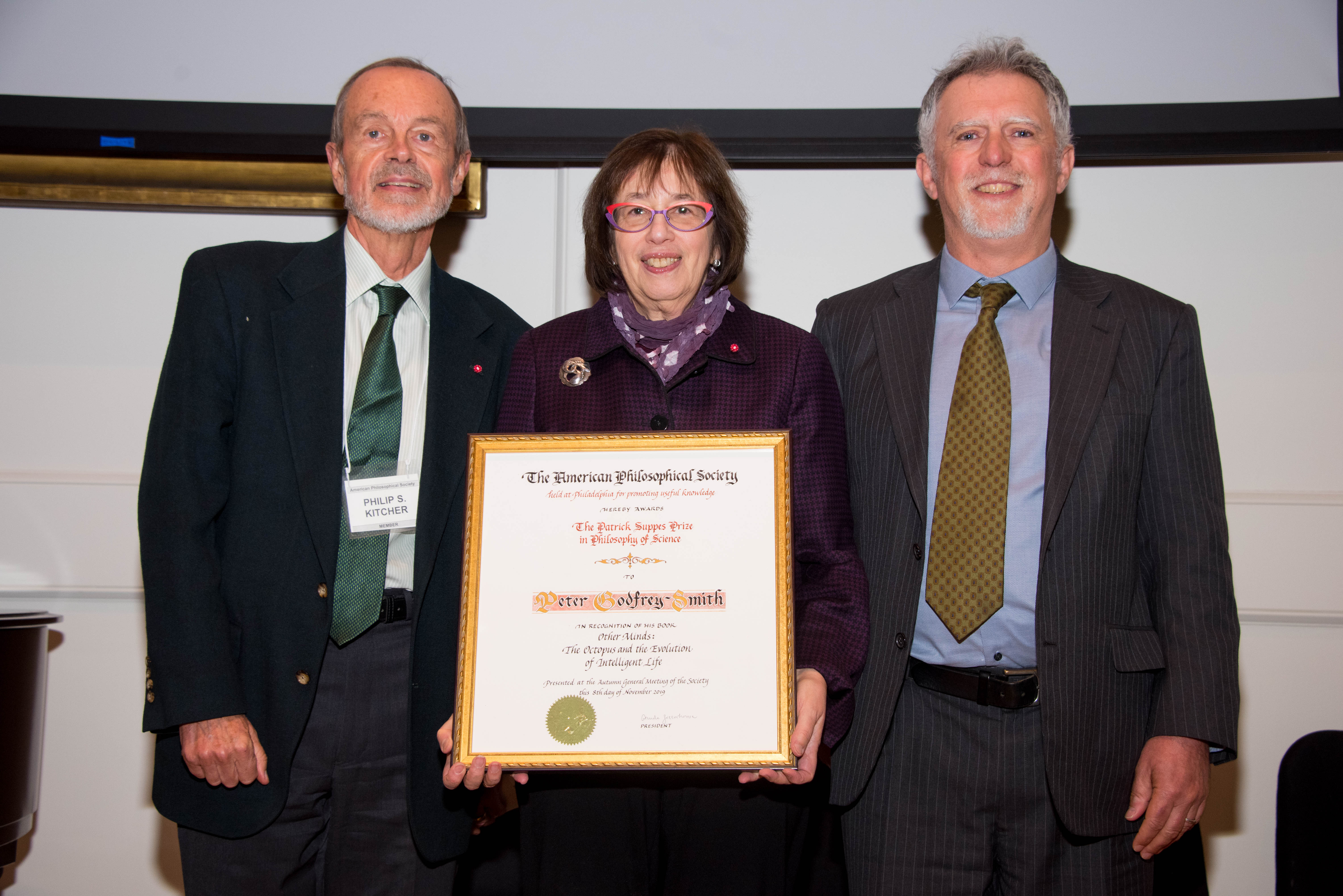 Linda Greenhouse holds the Suppes Prize certificate, standing between Phillip Kitcher and Peter Godfrey-Smith