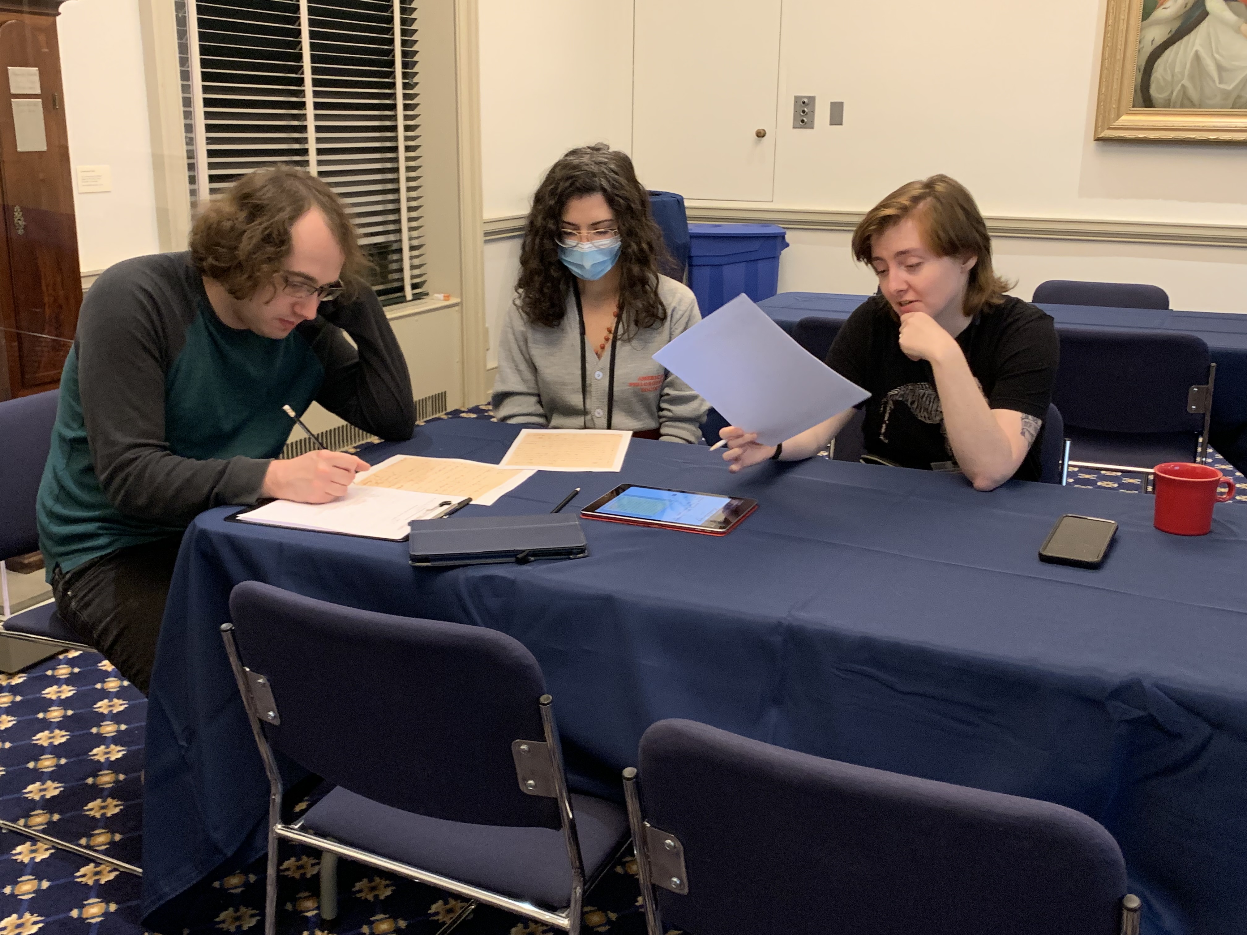 photo of three people sitting at a table working on transcription