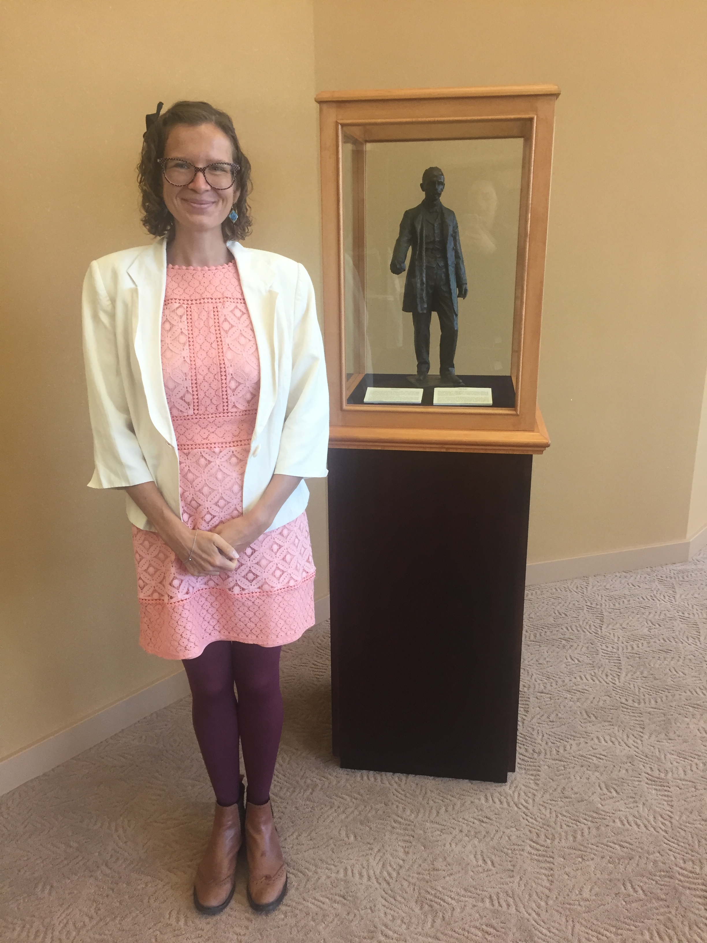 woman standing next to statue on podium