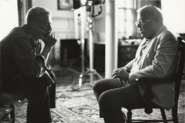 black and white photo of two men seated opposite one another for interview