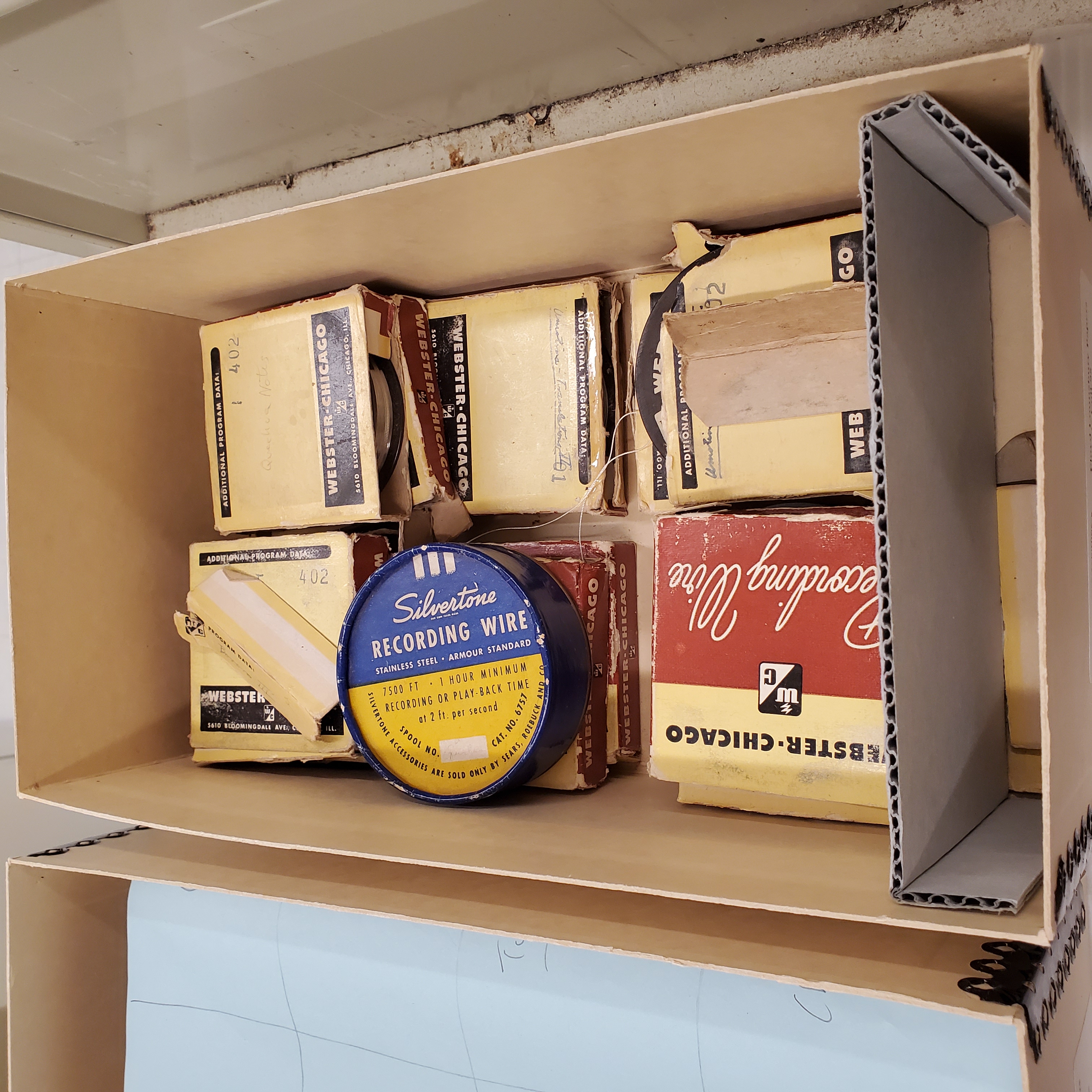 photo of several somewhat damaged microfilm boxes in a larger box