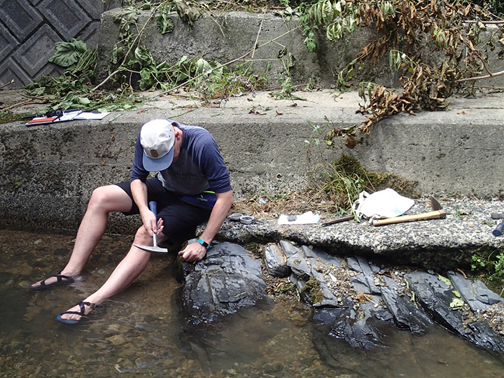 man taking sample from rock in river