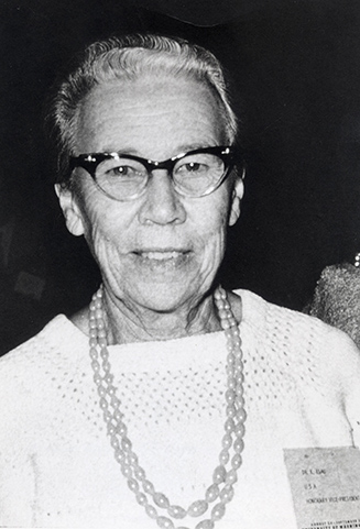 black and white headshot photo of woman wearing classes and necklace