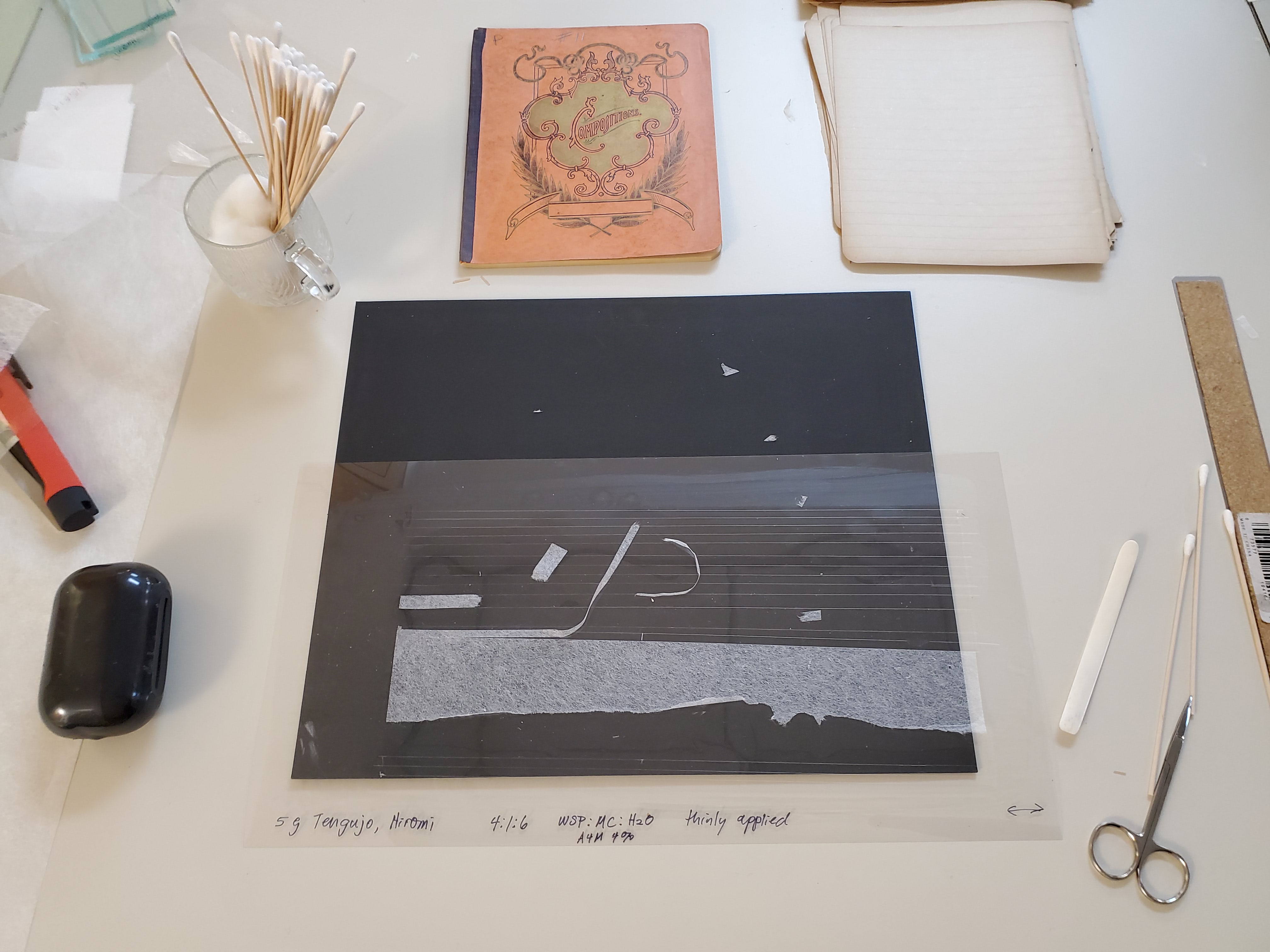 photo of conservation desk with mending tissue center, notebook top, and tools surrounding