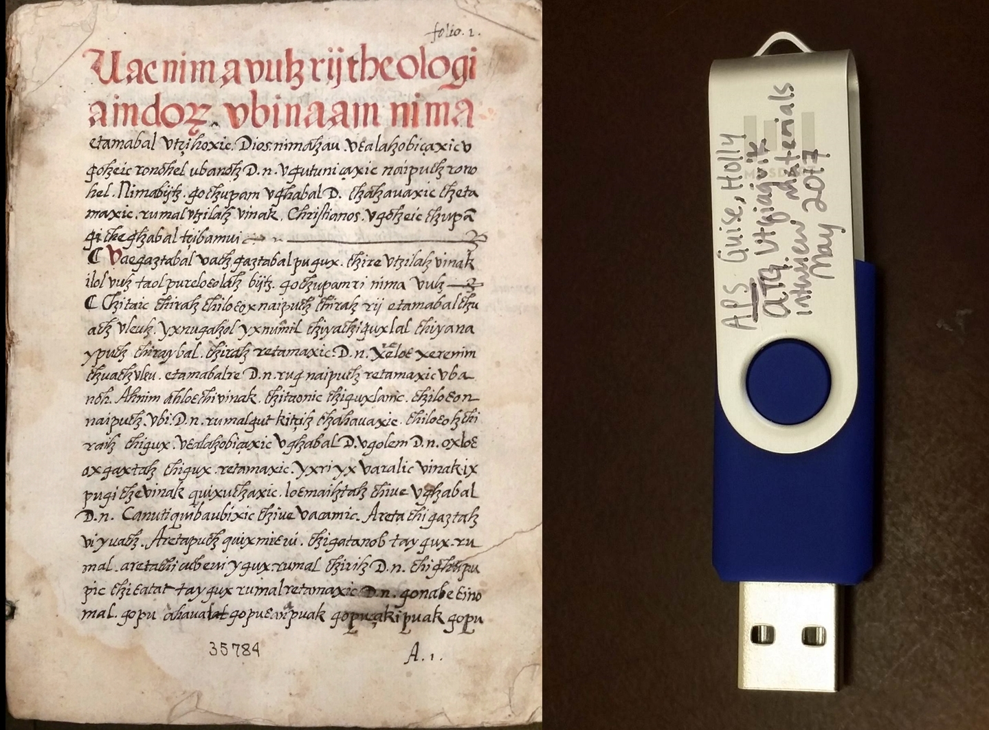 Una fotografía en color de un manuscrito escrito a mano en rojo y negro a la izquierda, y una unidad USB azul con texto escrito en ella a la derecha.