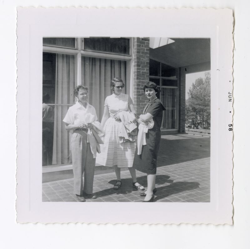 black and white photo of three women standing outside building