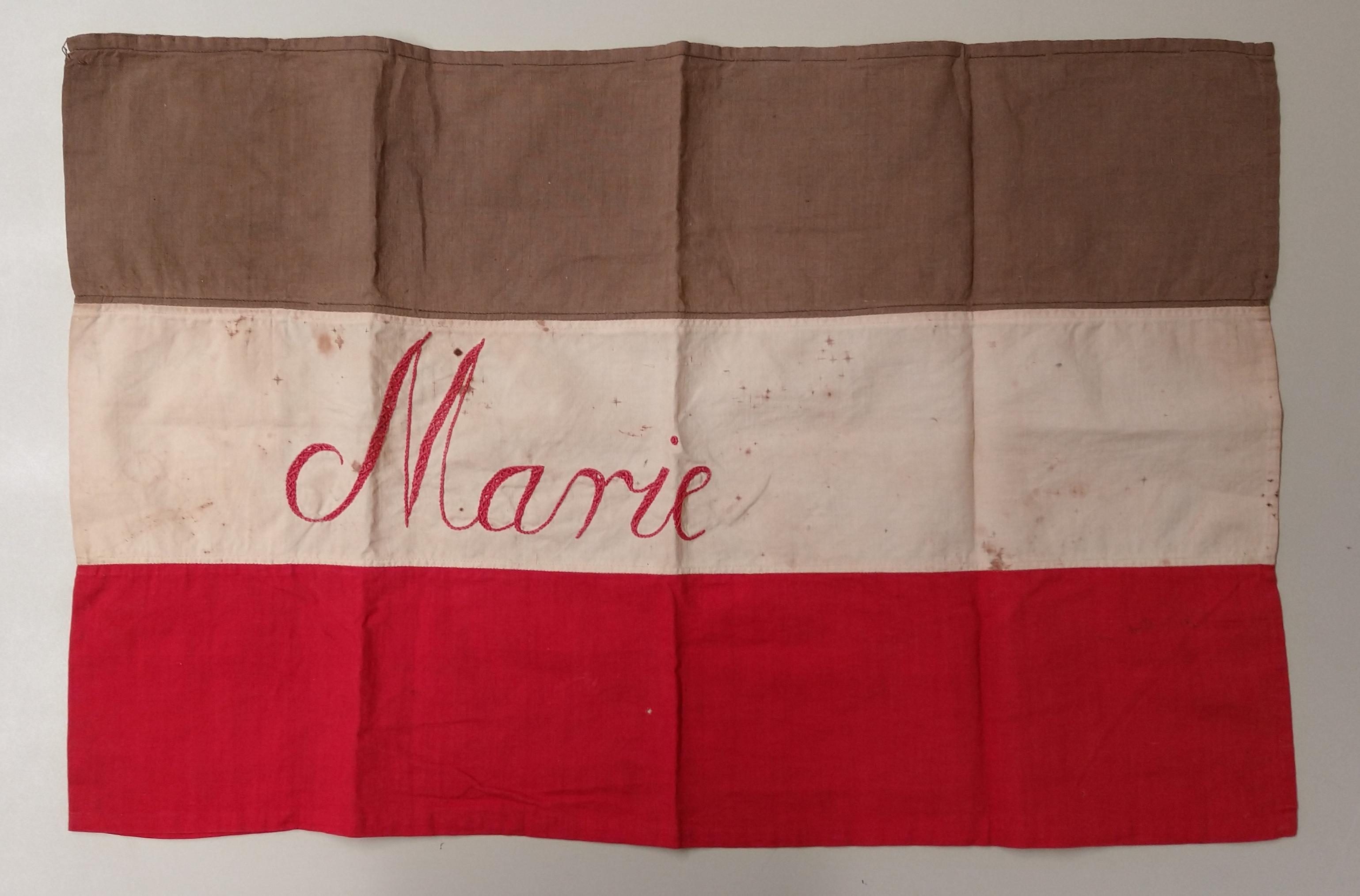 photo of brown, which, and red flag, with "Marie" written in red on the white portion in the center