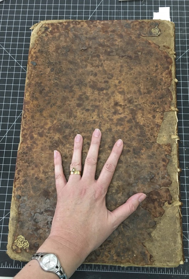 Back cover of Ben Franklin's Book of Common Prayer with conservator's hand