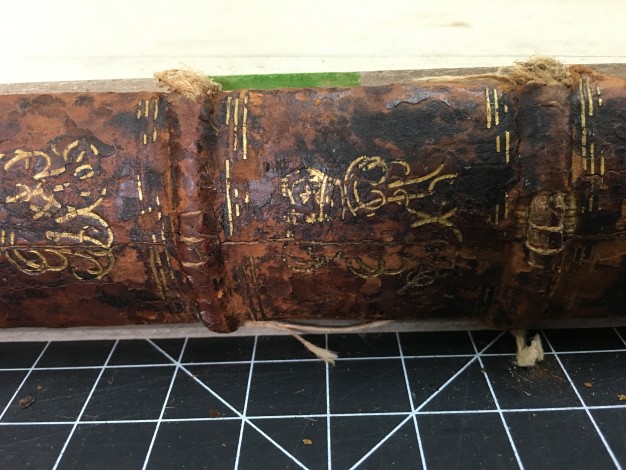 Loops of sewing thread visible through damaged leather on book spine