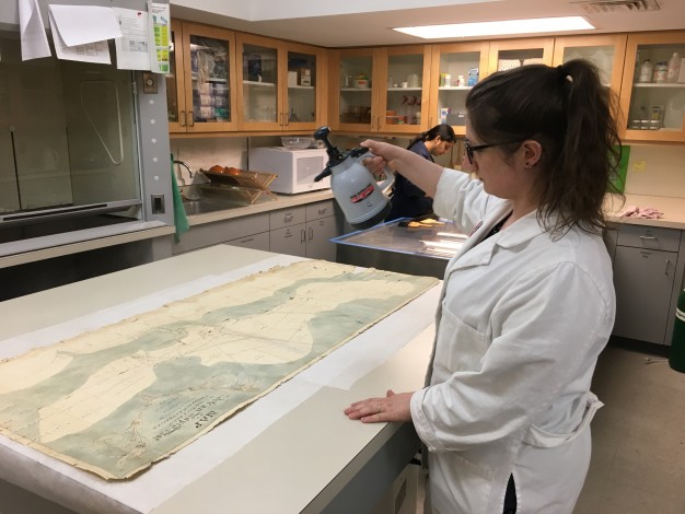 woman in lab coat spraying map