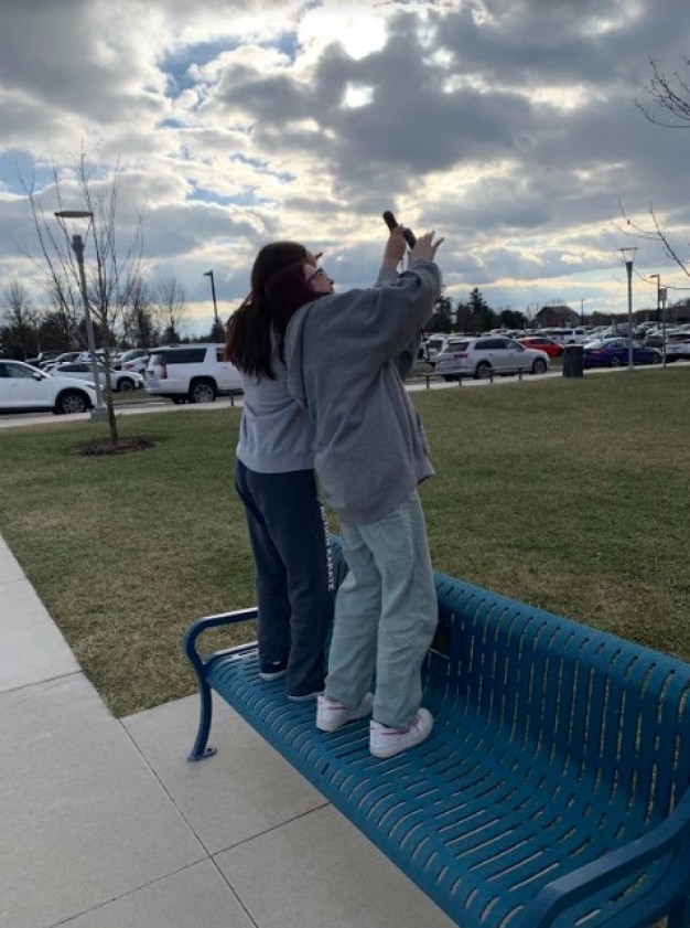 photo of two students standing on bench collecting weather data