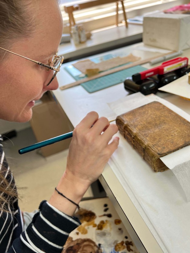 close up of woman's profile with tool working on spine of book