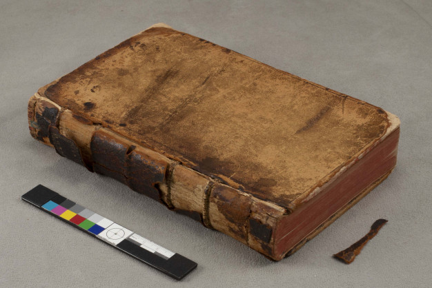 A worn leather-bound book on a gray table.