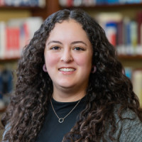 A woman poses for a photo in front of bookshelves.