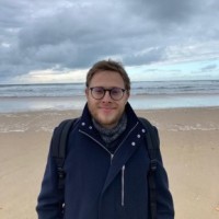 headshot photo of man standing on beach