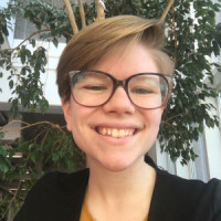 A picture of a smiling person in black-framed glasses