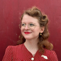 Portrait of a woman in a red dress against a red backround.
