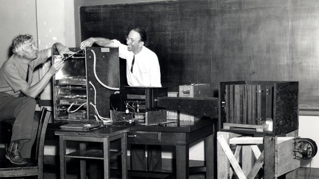 Two men work on scientific equipment