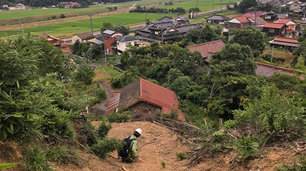 man crouched in landscape outside of Toyota Japan