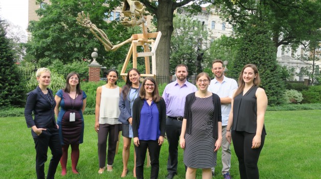 group standing in garden in front of giant sloth skeleton sculpture