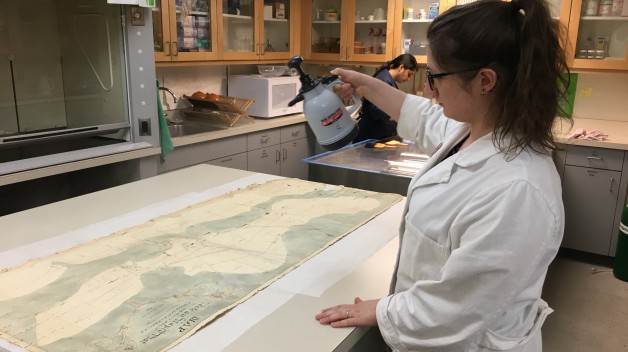 woman in lab coat spraying map