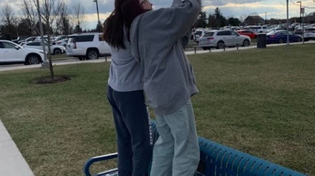 photo of two students standing on bench collecting weather data