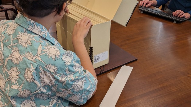 photo of woman seated looking through manuscript box