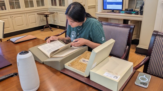 woman seated at table looking at books