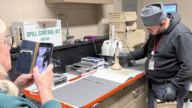 photograph of person taking a photograph of another person scanning a letter with equipment