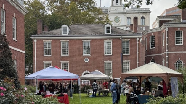 A picture of Jefferson Garden looking westward with Phil Hall in the background. The grounds have tents with people tabling in them and people doing the activities. 