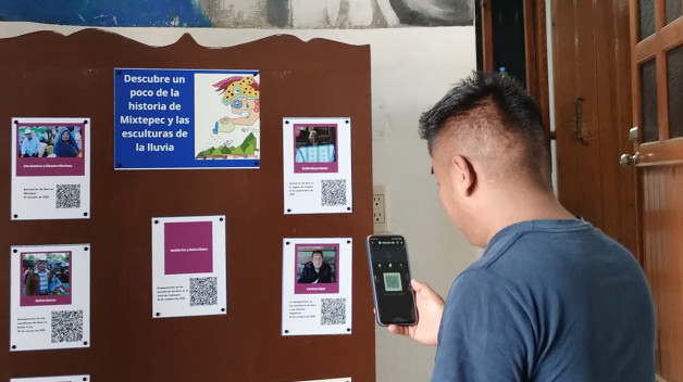 A man with a phone scans a QR code on a board full of colorful posters.