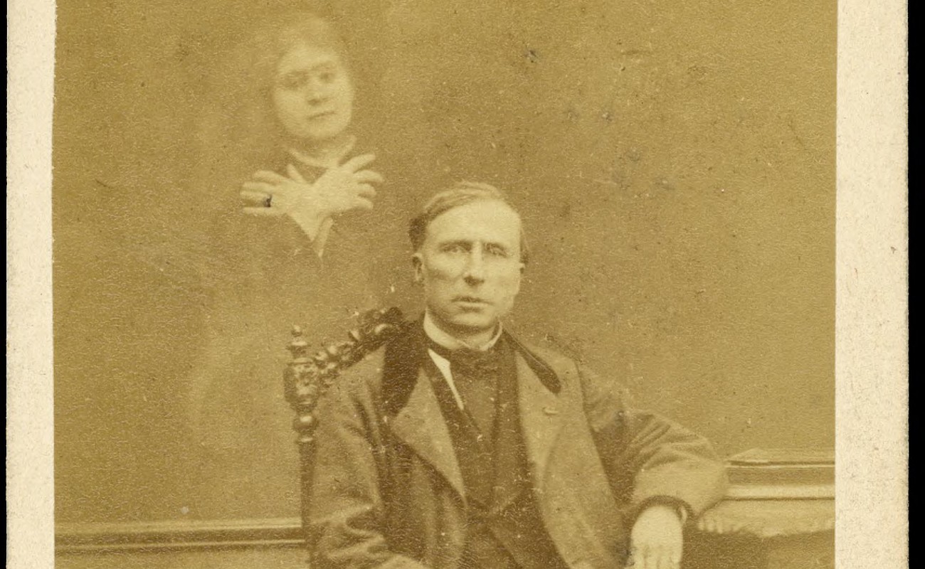 Photograph of seated man with spirit woman behind him