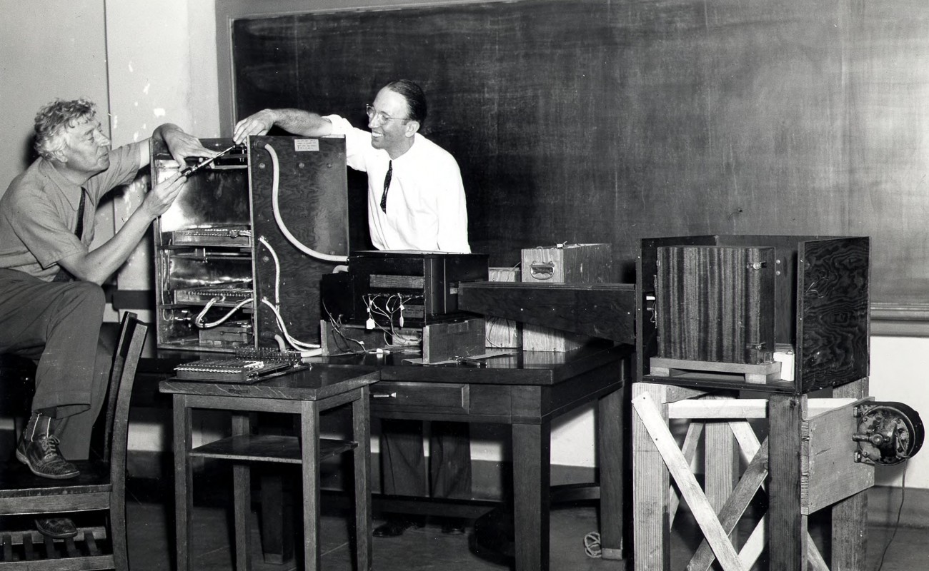 Two men work on scientific equipment