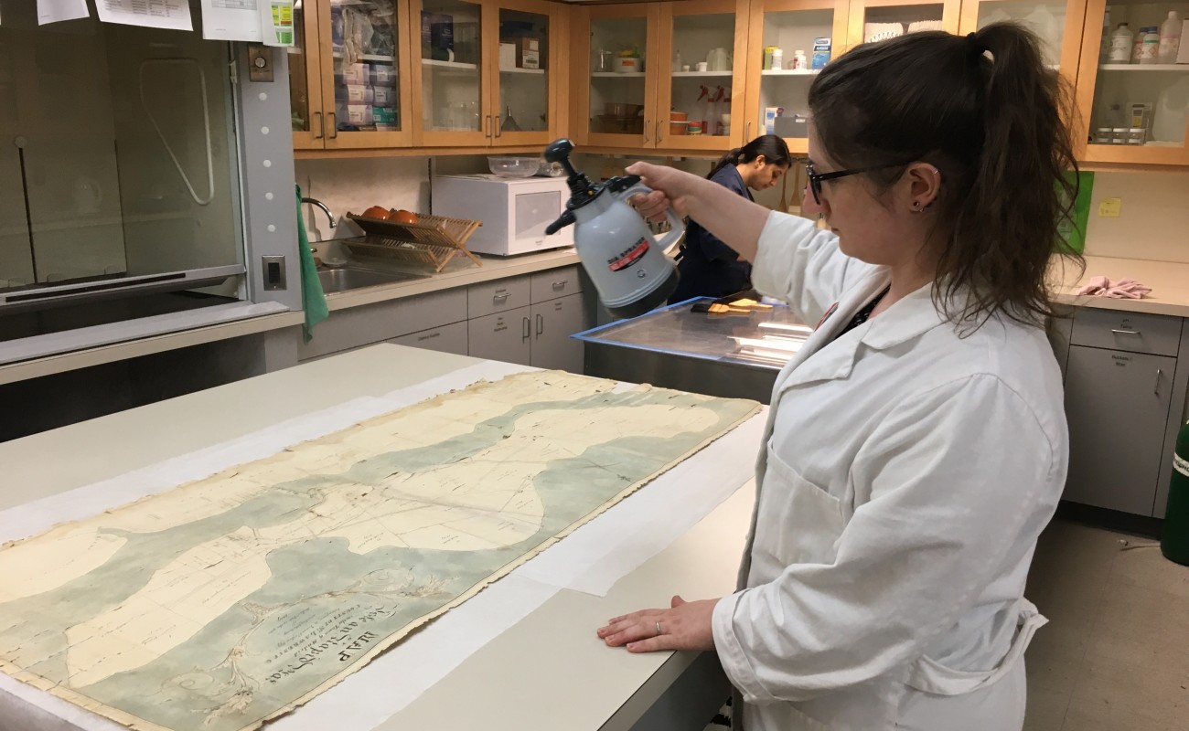 woman in lab coat spraying map