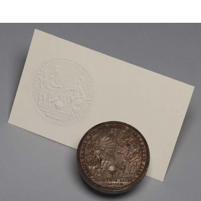 circular engraved metal seal and white card with seal impression