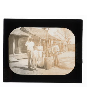 Black-and-white glass lantern slide of Creek family, girl posing with mortar and pestle, boy posing with bow and arrow.