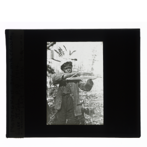 Black-and-white glass lantern slide of an Innu boy holding a crossbow at Lake St. John, Quebec.