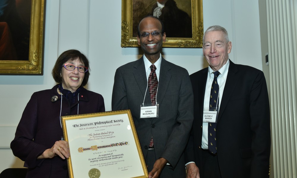 two men and one woman standing with certificate