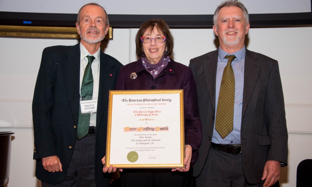 Linda Greenhouse holds the Suppes Prize certificate, standing between Phillip Kitcher and Peter Godfrey-Smith