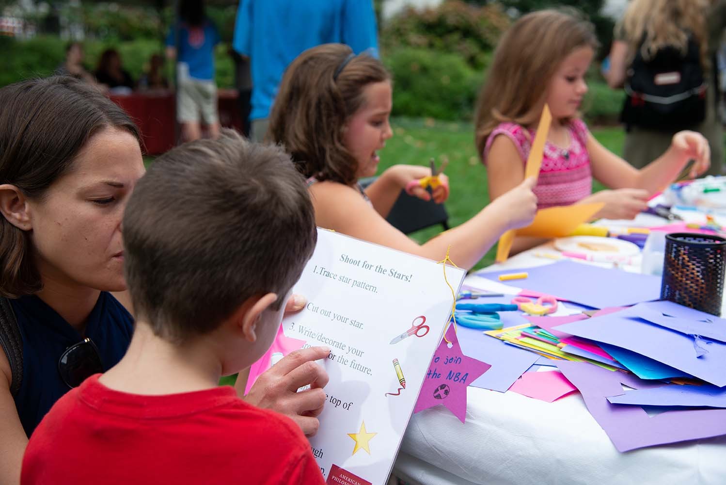 A picture of kids crafting paper stars at a table 