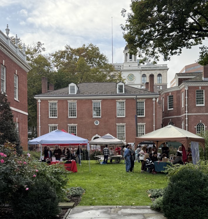 A picture of Jefferson Garden looking westward with Phil Hall in the background. The grounds have tents with people tabling in them and people doing the activities. 