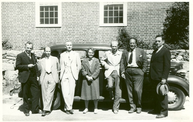 black and white photograph of group of seven people in front of a car parked beside a building, three men to each side of one woman (Barbara McClintock)