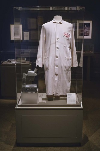 installation photograph of lab coat on mannequin with microscope beside it