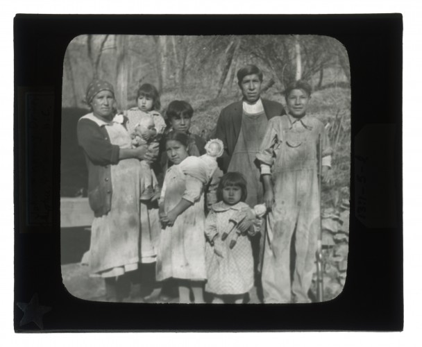 Black-and-white glass lantern slide of John and Nanny Driver and family standing outside.