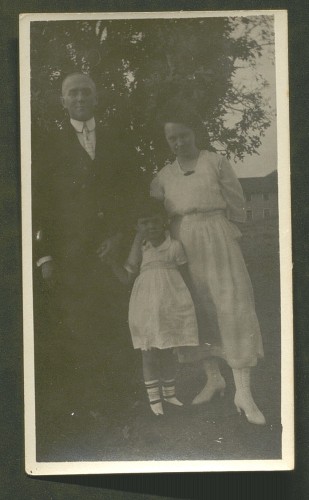black and white photo of man, woman, and child standing, posed for portrait